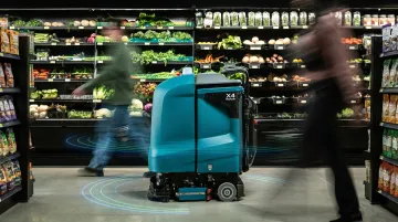 Autonomous floor scrubber robot navigating narrow retail store aisle with sensors active
