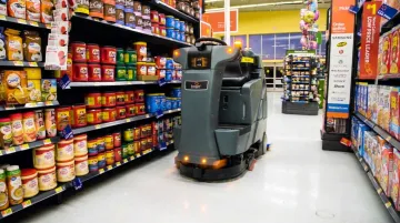 Large retail store autonomous floor scrubber robot operating in open shopping aisle