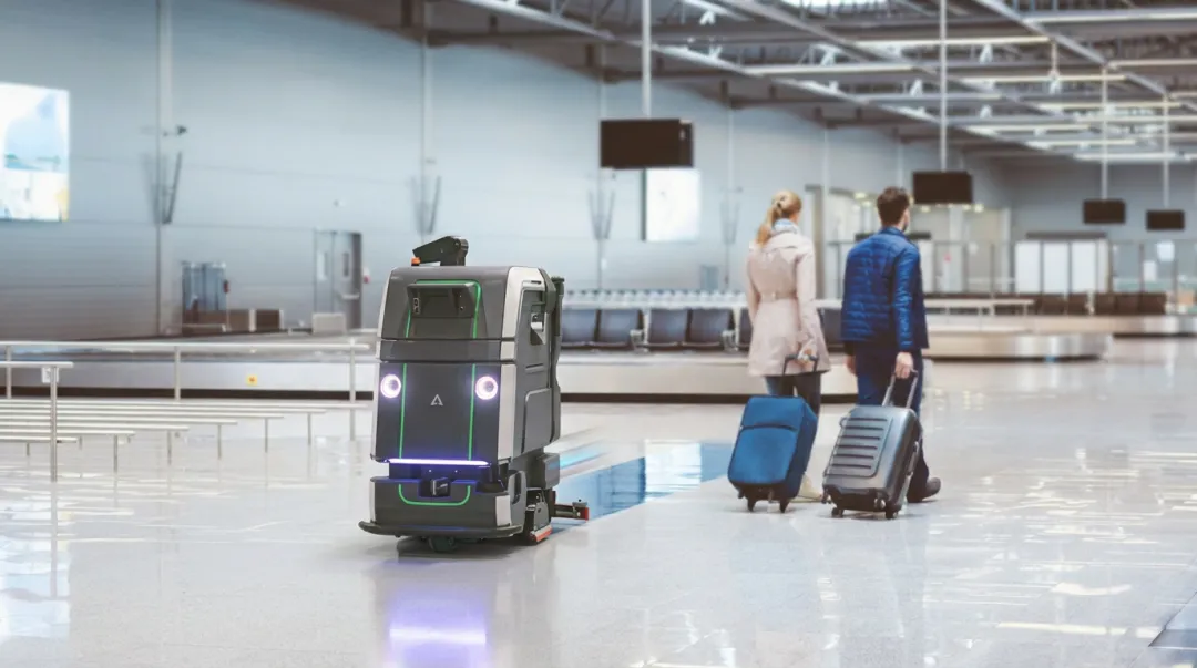 Commercial autonomous cleaning robot navigating large facility corridor during active operation