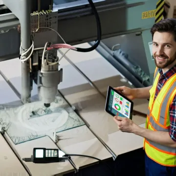 Manufacturing engineer reviewing real-time production analytics on tablet in modern facility