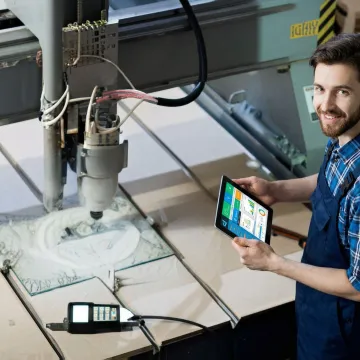 Manufacturing engineer reviewing real-time equipment monitoring data on tablet in factory