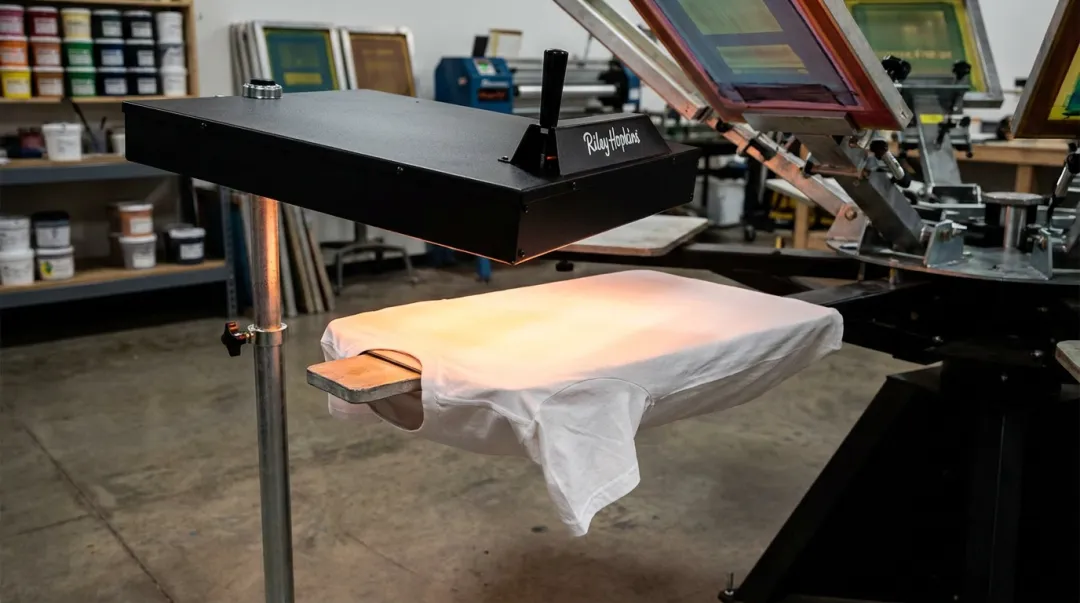 Commercial infrared flash dryer unit positioned over screen printing platen in production shop