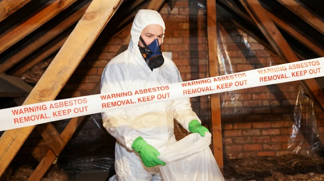 Certified asbestos abatement professional in full PPE working inside an older building