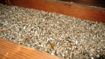 Close-up photo of loose-fill vermiculite insulation showing its pebble-like texture