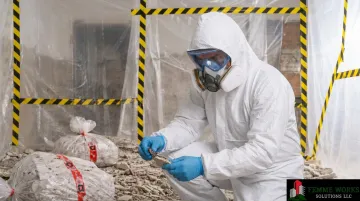 Certified remediation professional in full PPE removing hazardous materials from building interior