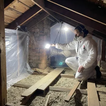 Technician inspecting attic insulation for energy rebate readiness