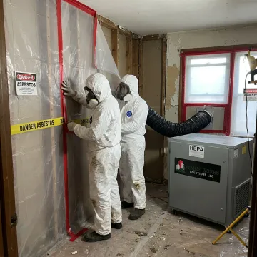 Licensed asbestos removal crew setting containment barriers