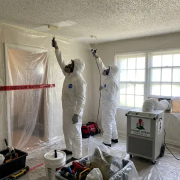 Crew removing asbestos popcorn ceiling with containment