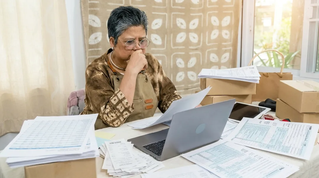 Small business owner reviewing tax compliance documents and financial paperwork at desk
