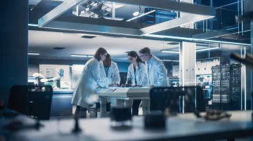 Diverse professional engineering team collaborating on medical device development project in modern office