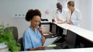 Medical secretary assisting patient at healthcare front desk reception