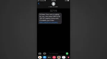 Mobile phone screen displaying abandoned cart SMS message with personalization discount code and direct purchase link