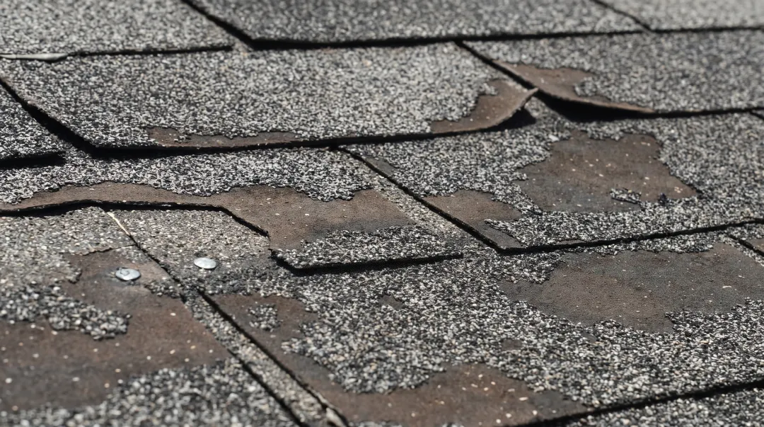 Curled and lifted asphalt shingles on residential roof edge
