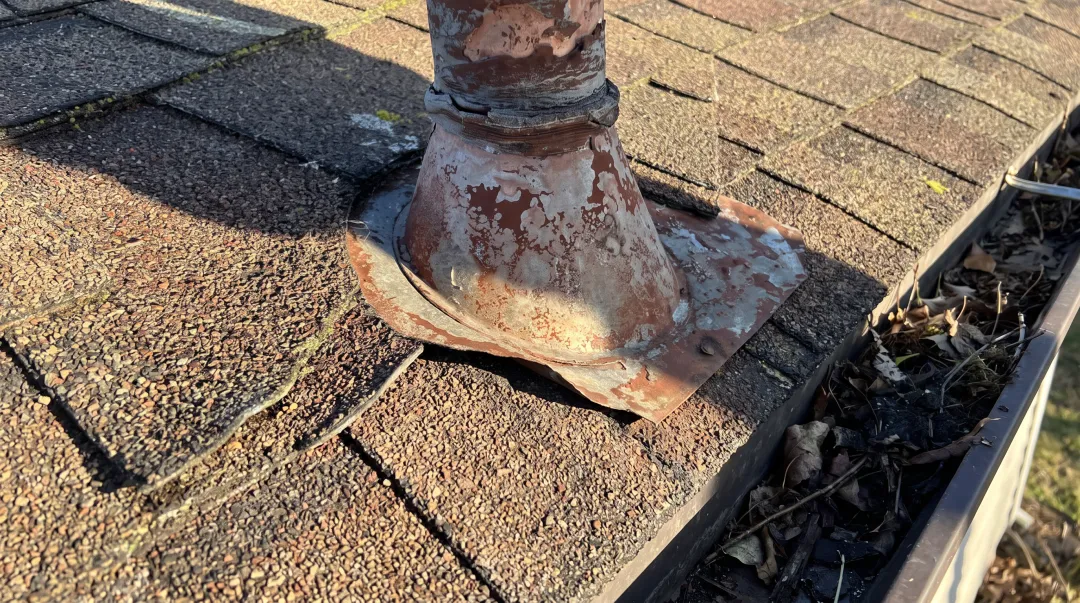 Damaged roof shingles and rusted flashing showing common leak causes