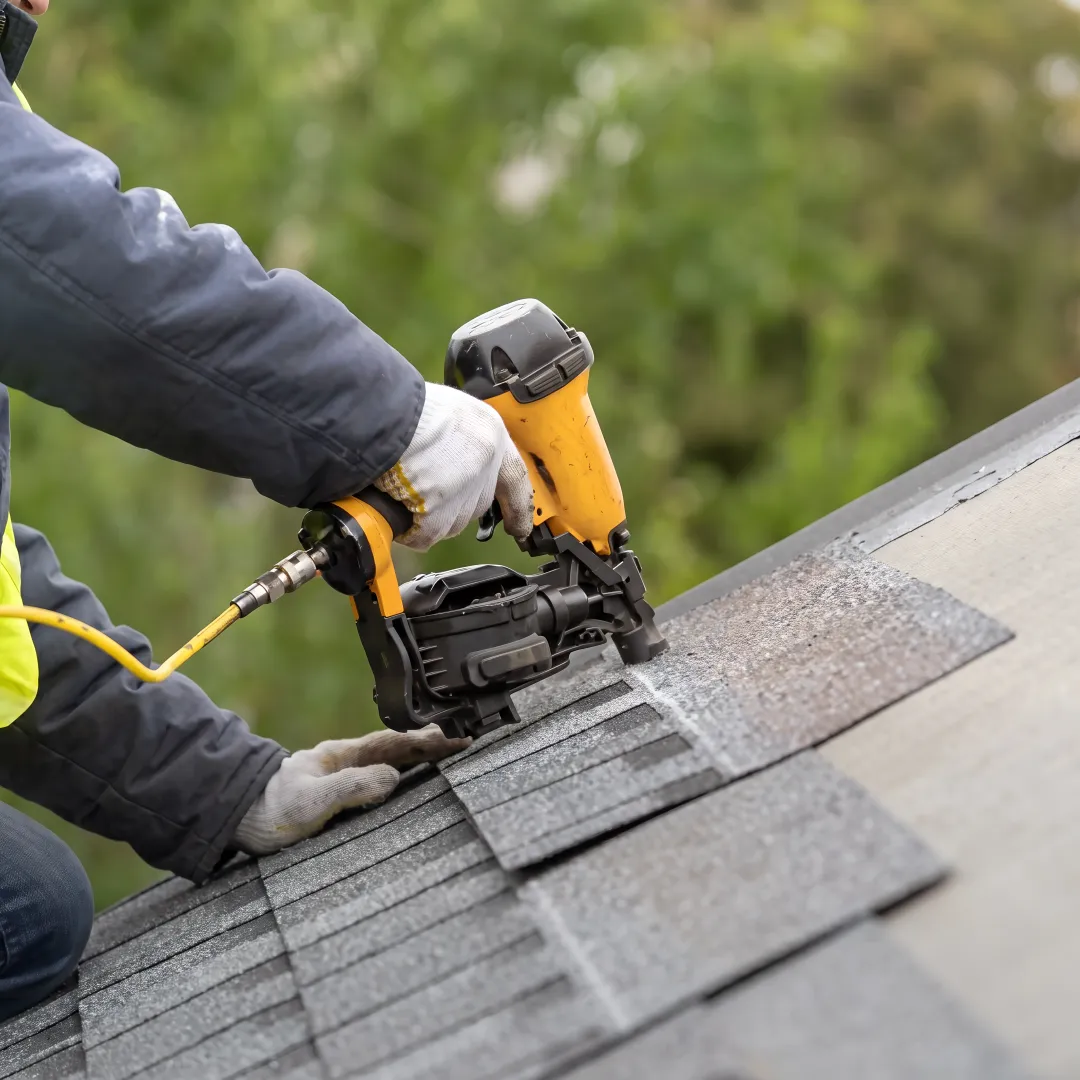 Contractor installing reflective roofing shingles