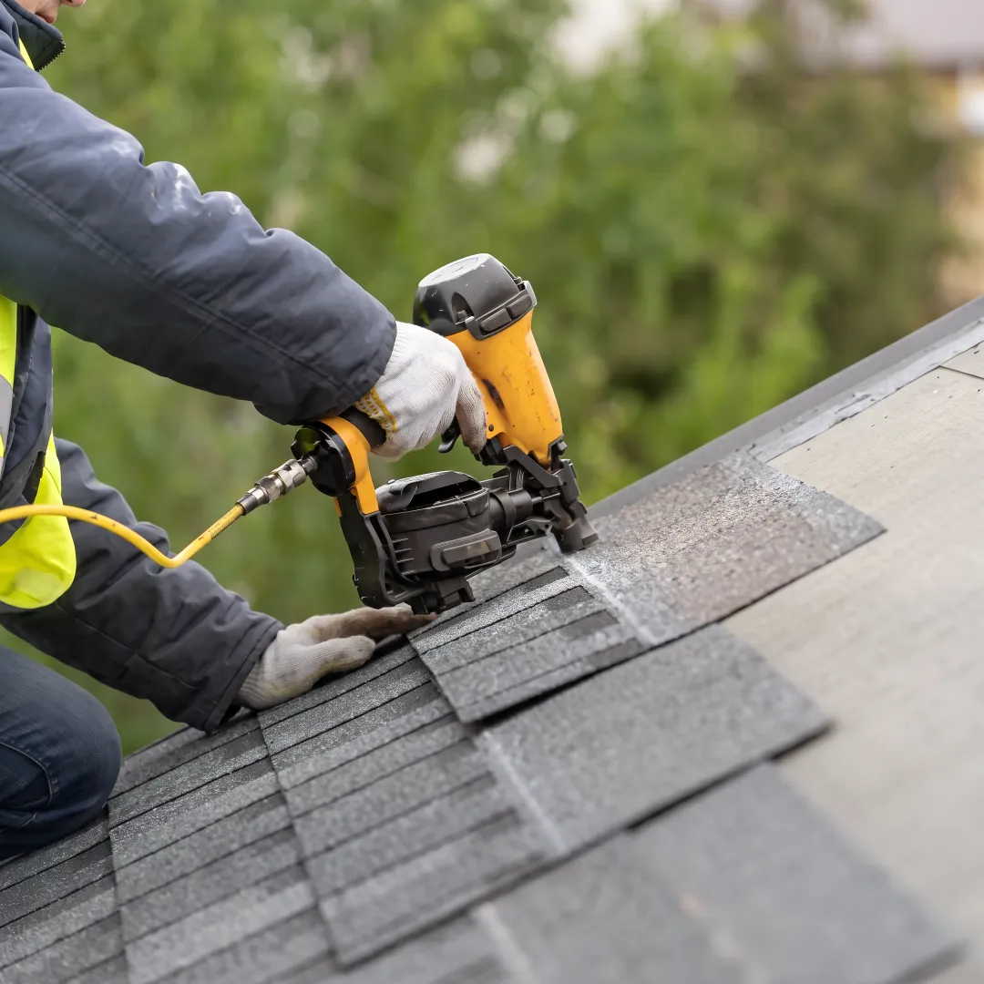 Roofing technician repairing damaged shingles