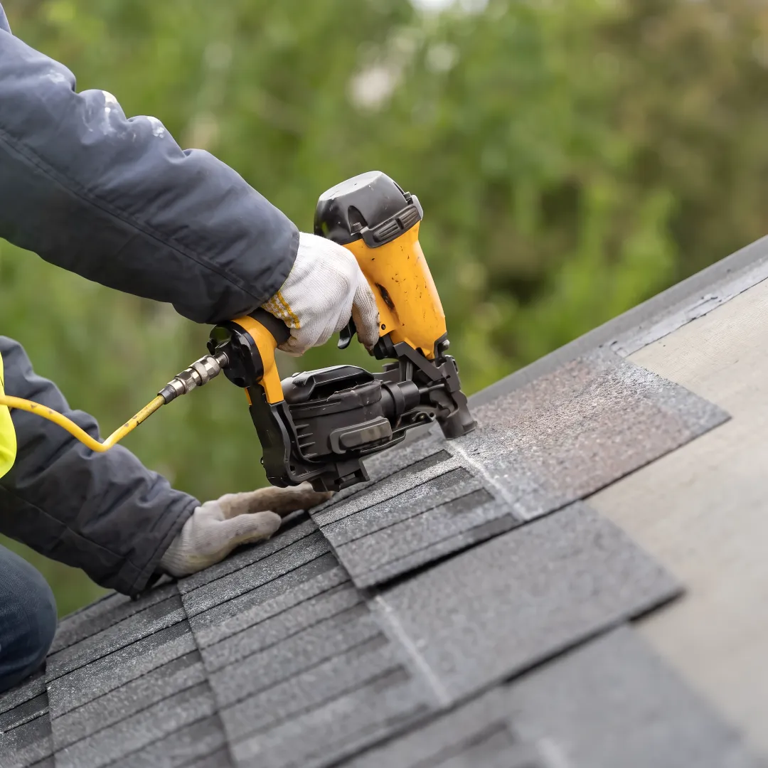 Roofing technician repairing damaged shingles