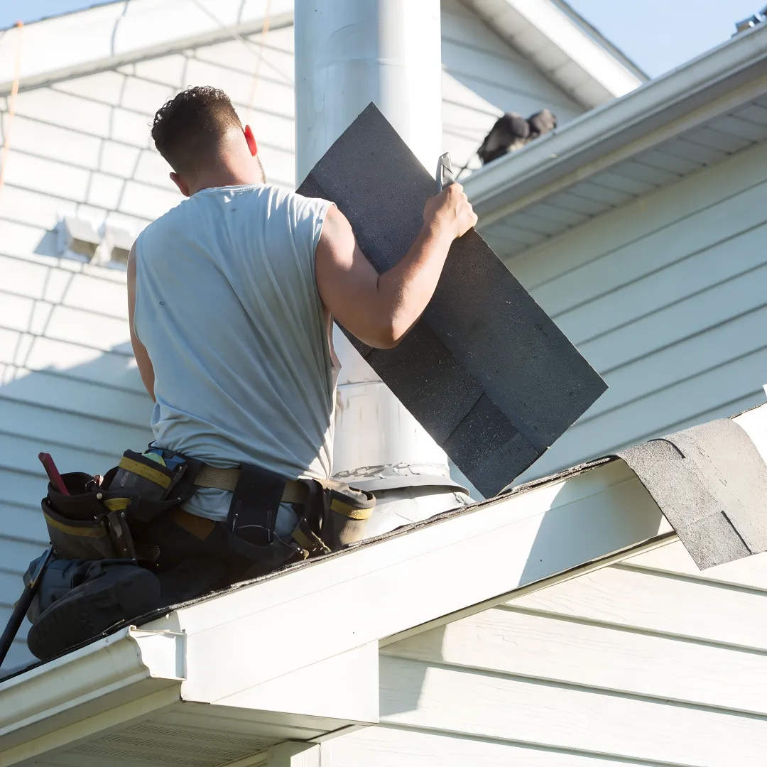 Roofing professional repairing shingles near a roof vent