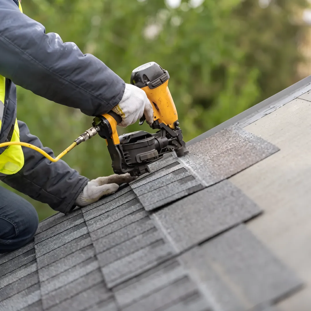 Roofer installing shingles on a gable roof