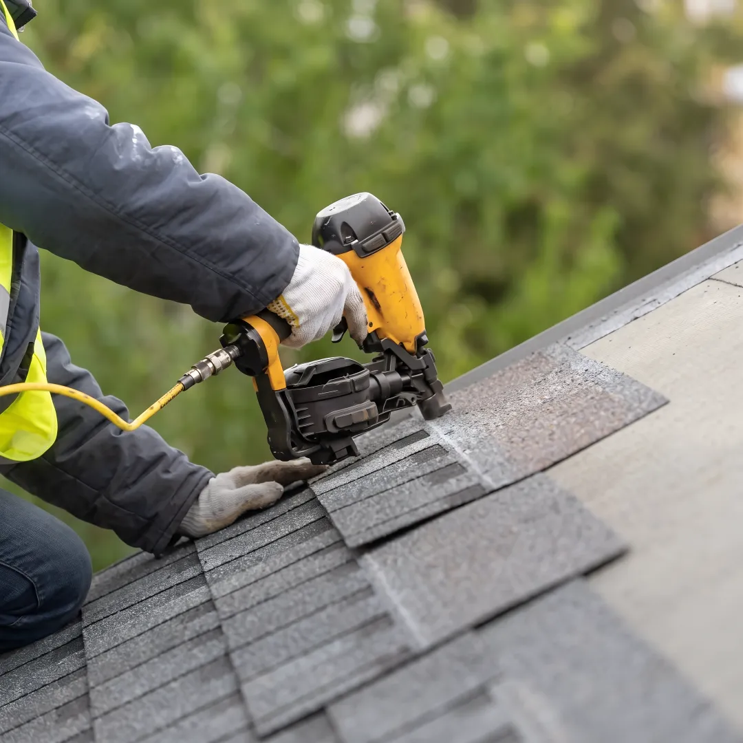 Installer placing reflective roof shingles