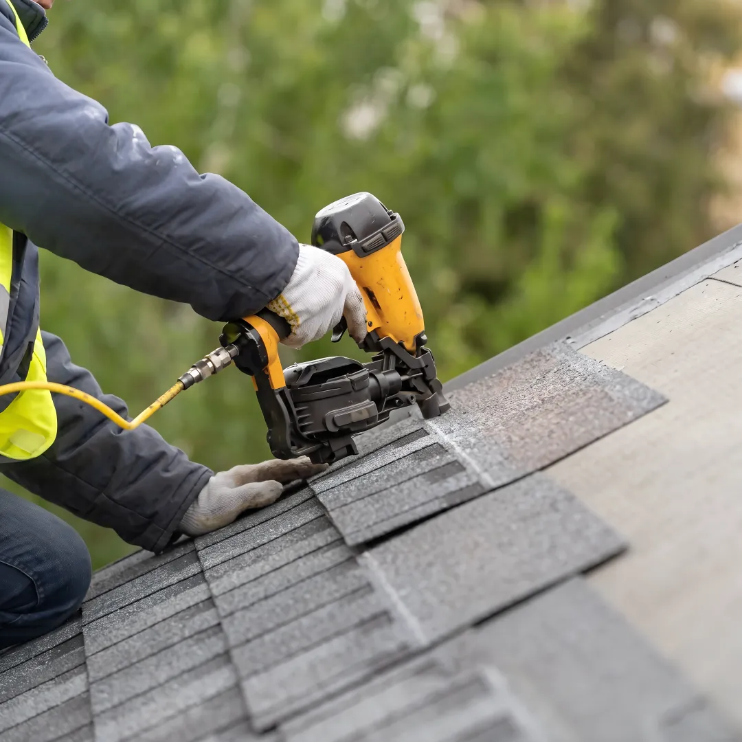 Roofing installer securing shingles on a home
