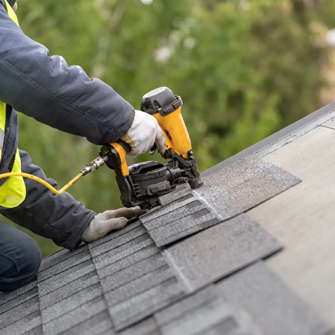 Roofing technician repairing damaged shingles