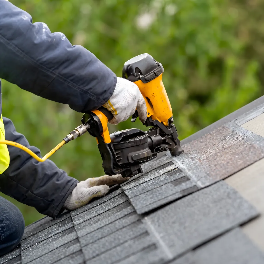 Roofing professional repairing shingles near roof flashing