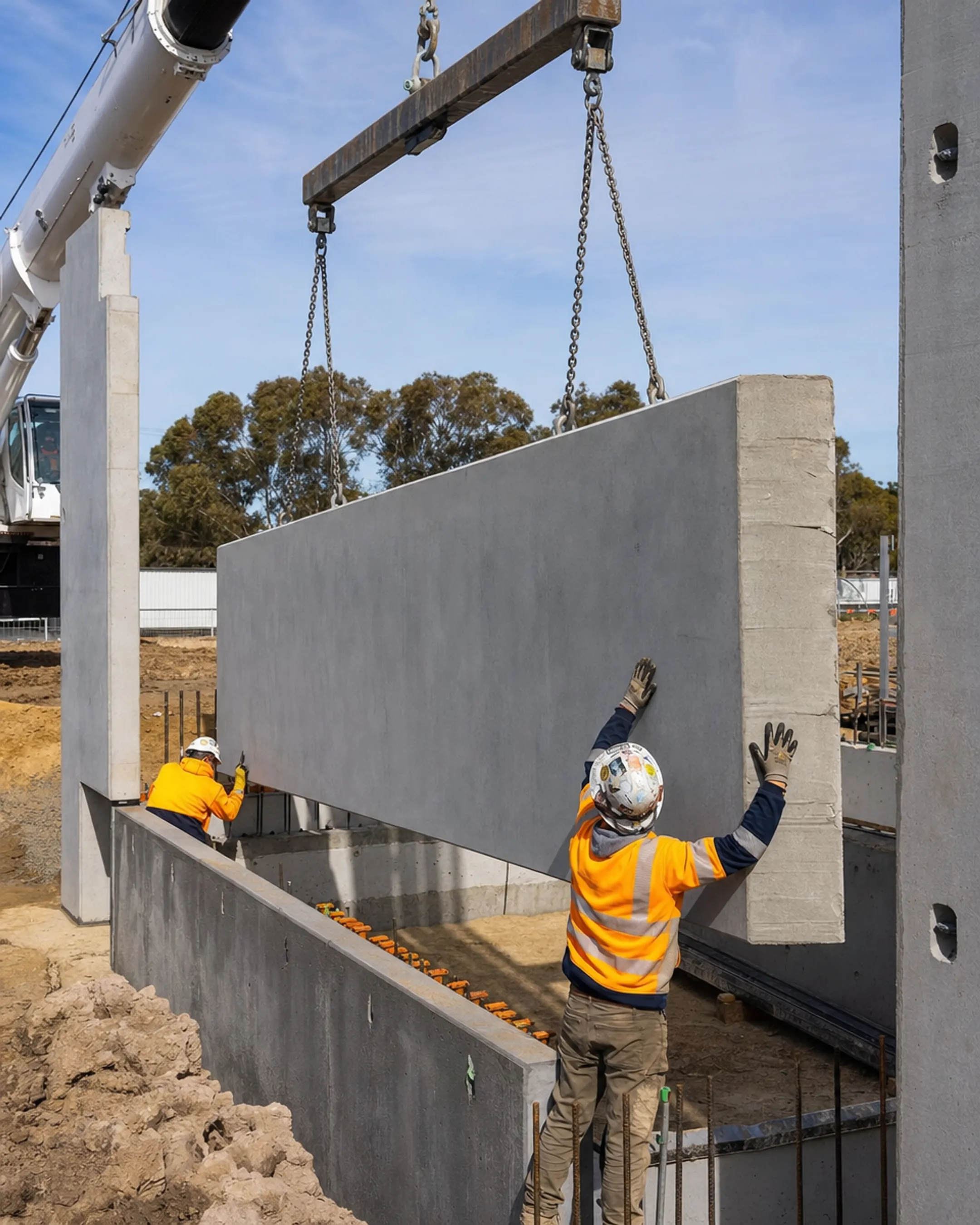 Crane lifting prefabricated steel wall panel into place on construction site