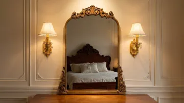 Ornate gilded wood bedroom mirror mounted above antique wood dresser traditional interior