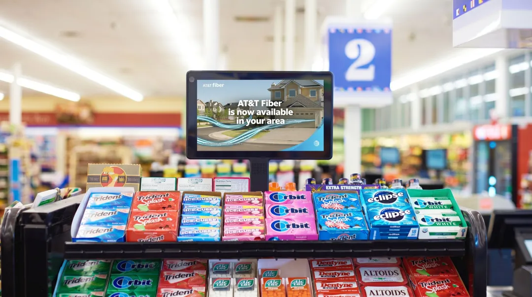 Retail in-store digital display screen at checkout counter promoting product offers