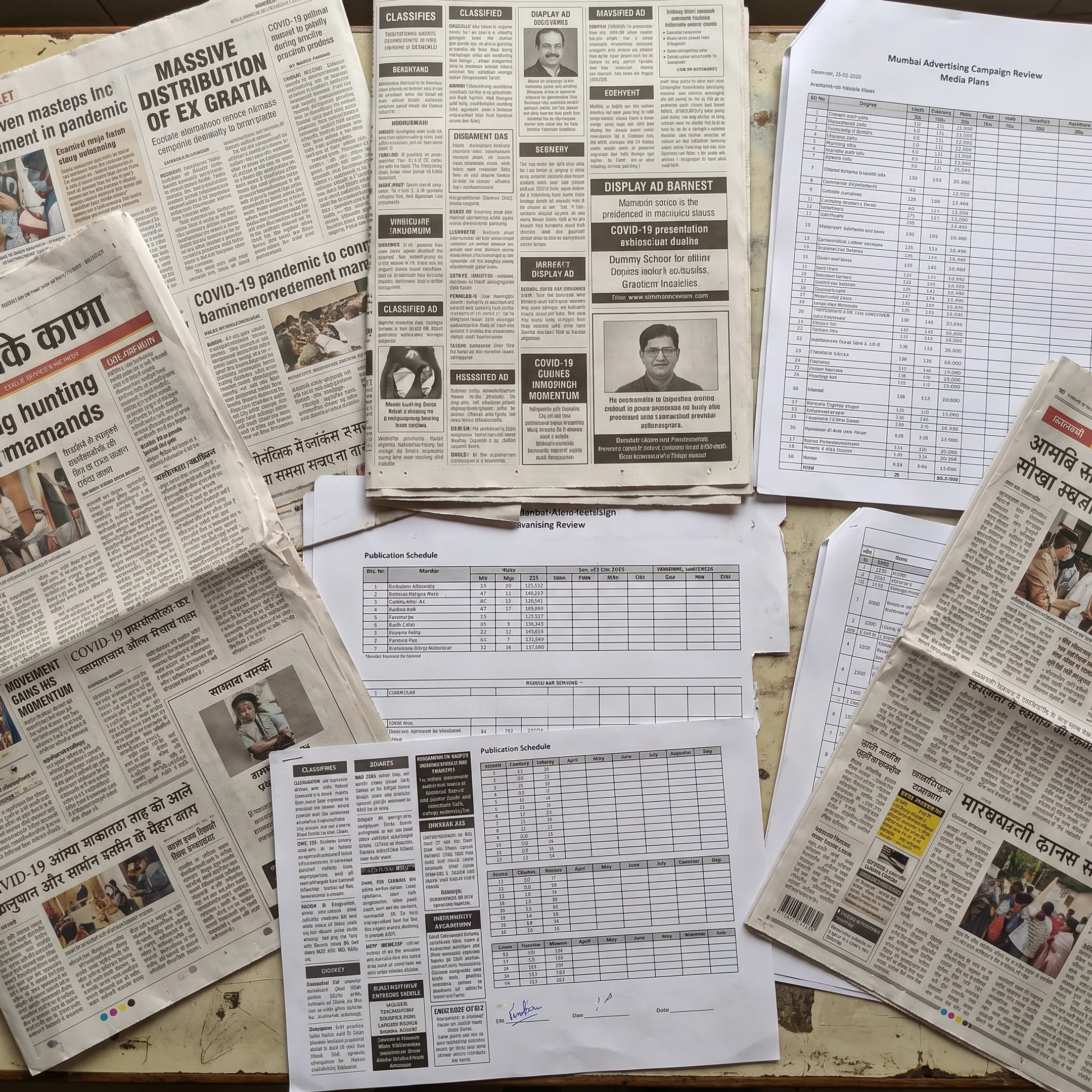 Newspaper ad placement and media planning materials on an agency desk
