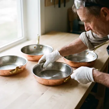 Handcrafted copper pans on a kitchen workbench
