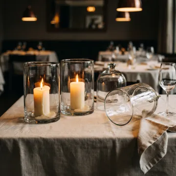 Glass hurricane candle vessels on restaurant table