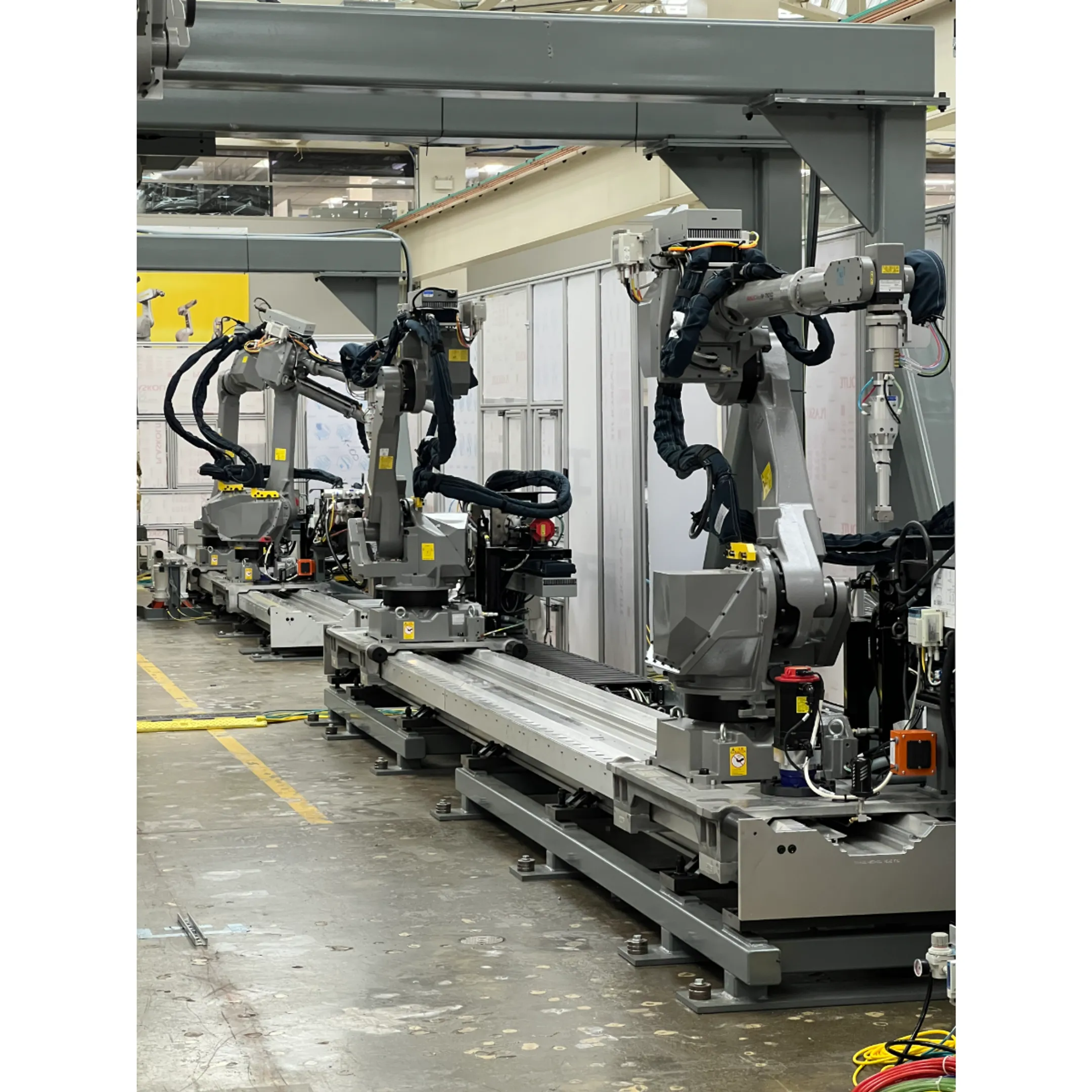 Robotic arm dispensing adhesive along a manufactured component in an industrial production cell