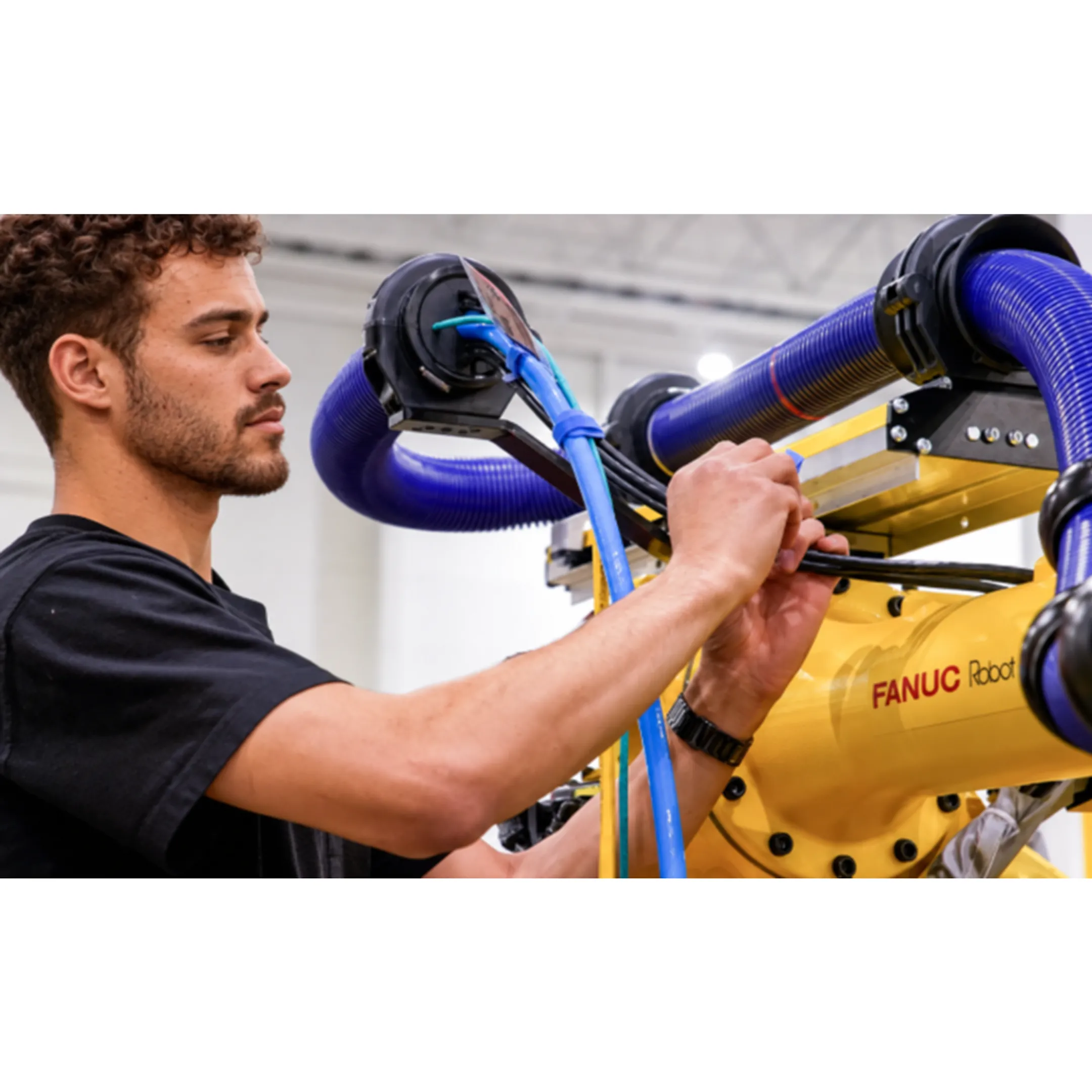 Engineer inspecting a FANUC robot teach pendant in a manufacturing environment