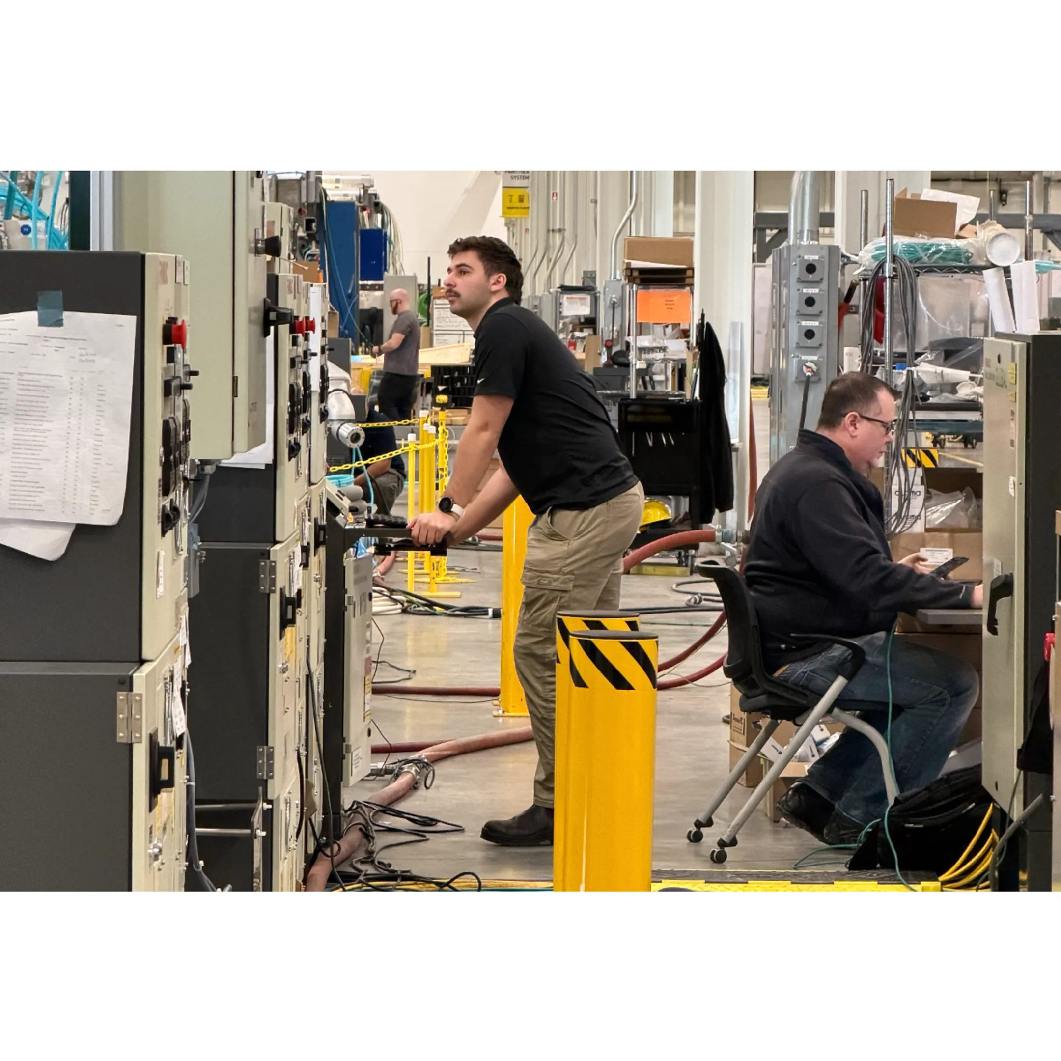 Automation specialist supporting a FANUC teach pendant near a robotic workcell