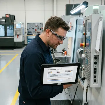 Technician using AI maintenance tools near CNC machine