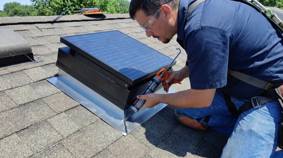 Professional roofer installing solar attic fan with proper flashing technique