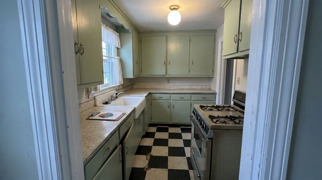 1950s Cape Cod kitchen interior with pastel cabinets laminate countertops and linoleum floor