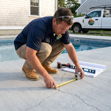 Contractor inspecting pool deck surface