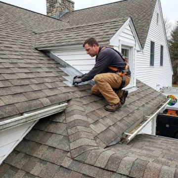 Roofing contractor inspecting shingles and flashing