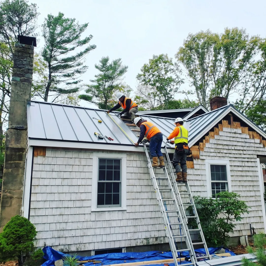Roofing crew measuring steel panels on a home