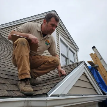 Contractor inspecting asphalt shingles during a roof assessment