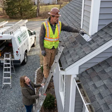 Roofing contractor reviewing repair plan with homeowner