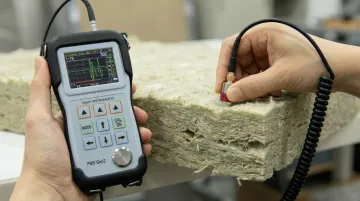 Ultrasonic thickness measurement probe applied to porous fibrous material surface in lab setting