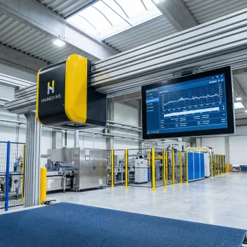 Close-up of contactless M-Ray thickness measurement sensor over moving manufacturing panel