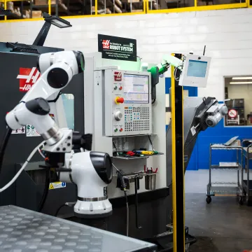 Operator reviewing uptime data beside CNC machine