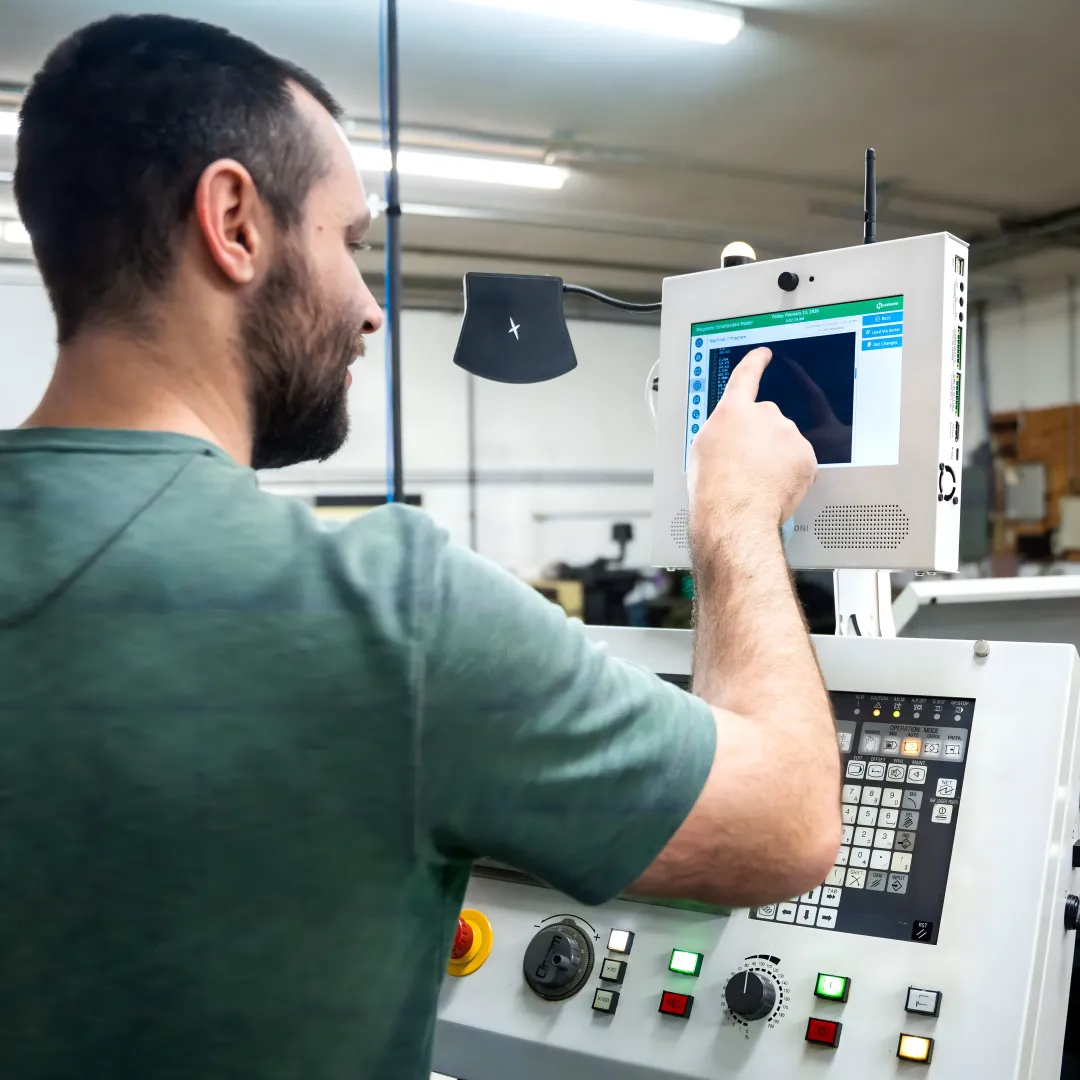 Operator viewing machine health dashboard beside CNC equipment