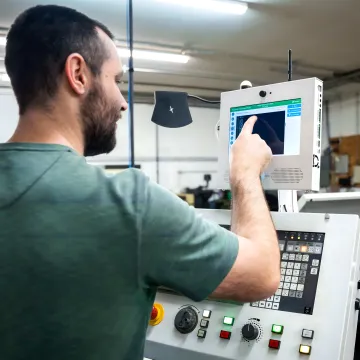 Operator viewing machine health dashboard beside CNC equipment