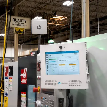 Technician reviewing manufacturing dashboard near CNC machines
